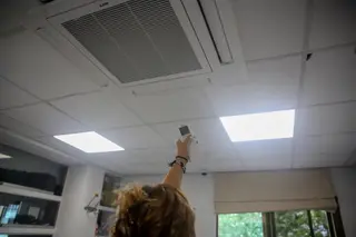 Una mujer enciende el aire acondicionado en una oficina