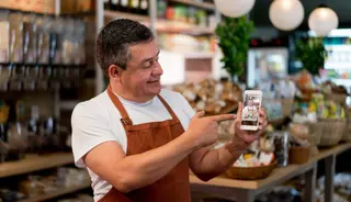 El dueño de una pyme de alimentación muestra en su smartphone un sistema para vender online sus productos. Archivo