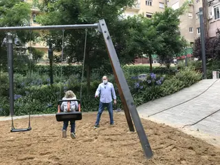 Una niña y su abuelo juegan en los columpios