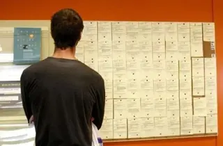 Un joven observa ofertas de empleo en un tablón de anuncios