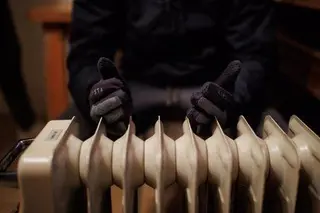 Una persona trata de calentarse con un radiador eléctrico. EP