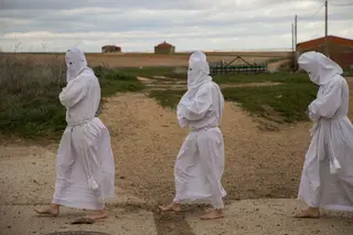 Unos penitentes en la Procesiónn de La Carrera en Villarrí­n de Campos (Zamora), al fondo unos palomares. | Eduardo Margareto