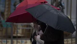 Viandantes pasean con el paraguas bajo la lluvia