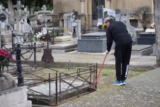 Imagen de un hombre limpiando una sepultura en San Atilano en el Día de Todos los Santos