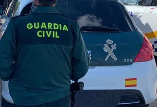 Un agente de la Guardia Civil junto a un vehículo oficial. Archivo.