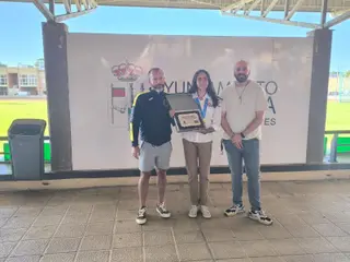 Ana Bailón muestra con orgullo la placa de reconocimiento y la medalla de oro