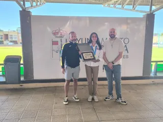Ana Bailón muestra con orgullo la placa de reconocimiento y la medalla de oro