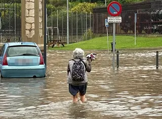 Una mujer camina zapatillas en mano ante la anegación de la zona de la estación de tren en Zamora