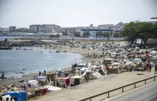 Varios inmigrantes acampados en una playa, a 31 de agosto de 2026, en Ceuta. Marcos Moreno. Europa Press