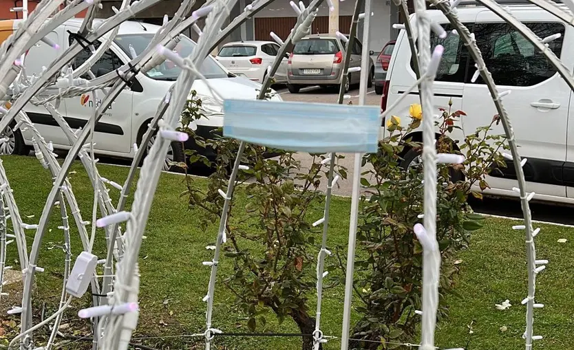 Una mascarilla colgada en la iluminación navideña