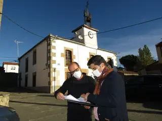 El Portavoz Municipal del PSOE, Samuel Mayor, junto a Eduardo Folgado en la plaza de Moraleja de Sayago con el Ayuntamiento al fondo en una reciente visita a la localidad