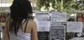 Una joven observa varios carteles de viviendas en alquiler