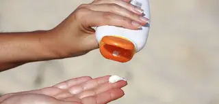 Una mujer se dispone a aplicar fotoprotector solar contra el sol
